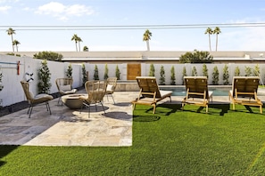 An outdoor patio area with lounge chairs, a fire pit, and a swimming pool. - Reesor: Scottsdale Home with Private Pool & Spa (Scottsdale)