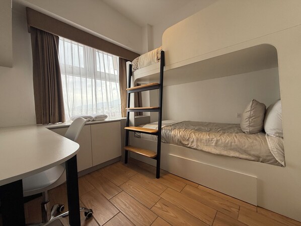 Habitación pequeña con una cama litera, un escritorio y una silla.