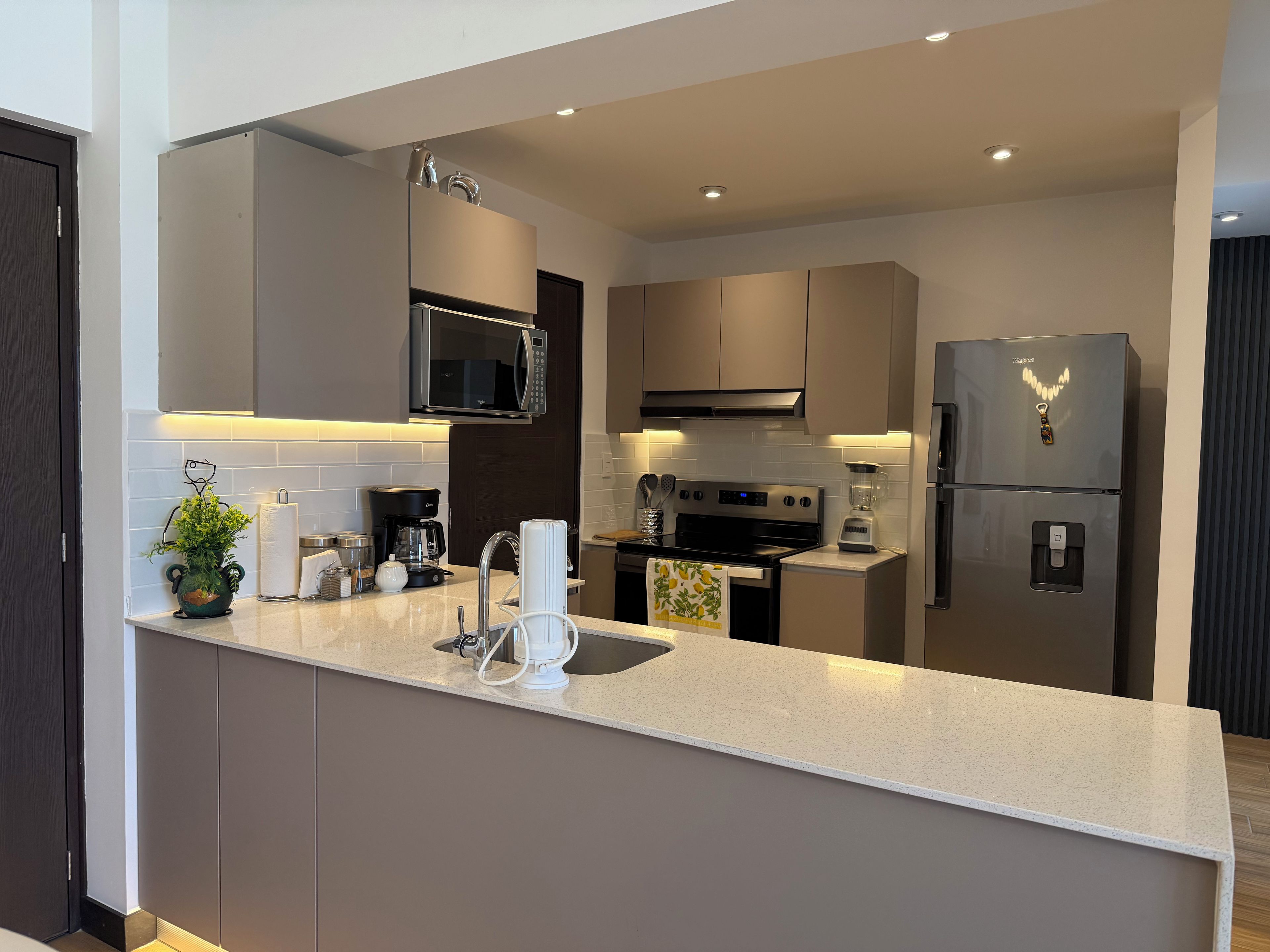 A modern kitchen with a central island, stainless steel appliances, and a backsplash.
