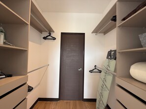 Un pasillo estrecho con suelo de madera, una puerta oscura y estanterías empotradas a ambos lados.