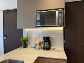 A modern kitchen with a built-in microwave, a coffee maker, and a potted plant on the counter.