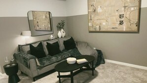 A living room with a grey sofa, black cushions, a black coffee table, and a painting on the wall. - Modern New 2BR beside Park, 14m WEM, 4m Grocery (Edmonton)