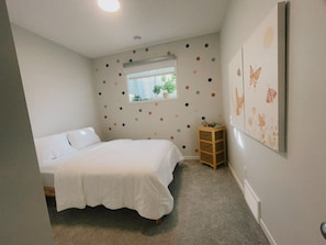 Ein Schlafzimmer mit einem Bett, einem Fenster, einer Wand mit Punkten und einem kleinen Holzschrank.