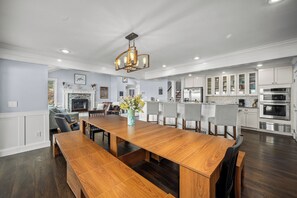 Un comedor amplio con una larga mesa de madera, sillas y un jarrón decorativo.