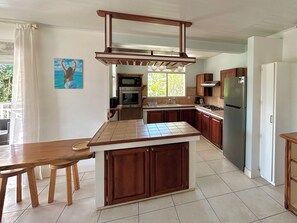 A kitchen with a central island, wooden cabinets, a stainless steel refrigerator, and a window providing natural light.