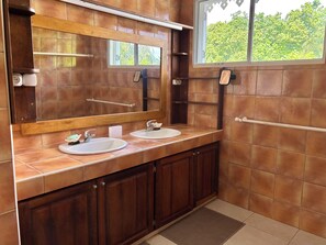 A bathroom with two sinks, a large mirror, and a window.