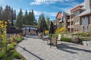 A patio area with outdoor seating, a covered section, and a view of residential buildings. - Creekside Gondola, pool, hot tub, BBQ, & free parking! (Whistler)