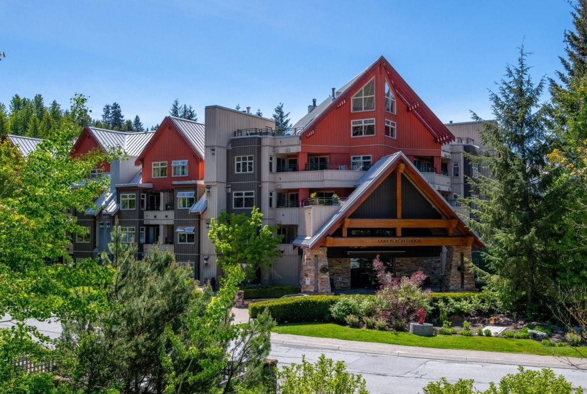 A multi-story lodge with a prominent red roof, stone facade, and a well-maintained garden.