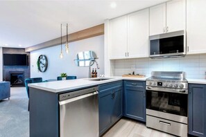 A modern kitchen with a built-in dishwasher, a stove, and a microwave. - Creekside Gondola, pool, hot tub, BBQ, & free parking! (Whistler)