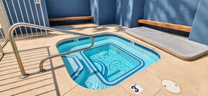A small, rectangular swimming pool with a metal ladder, a wooden bench, and a tiled edge. - The Saguaro - King • Arcade • Pool/Spa • Gym • W/D (Tempe)