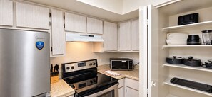 A compact kitchen with a stainless steel refrigerator, a built-in oven, a microwave, and a coffee maker. - Next to ASU • King Bed • Arcade • Pool/Spa • Sleeps 8 • Pets • 65" TV • W/D (Tempe)