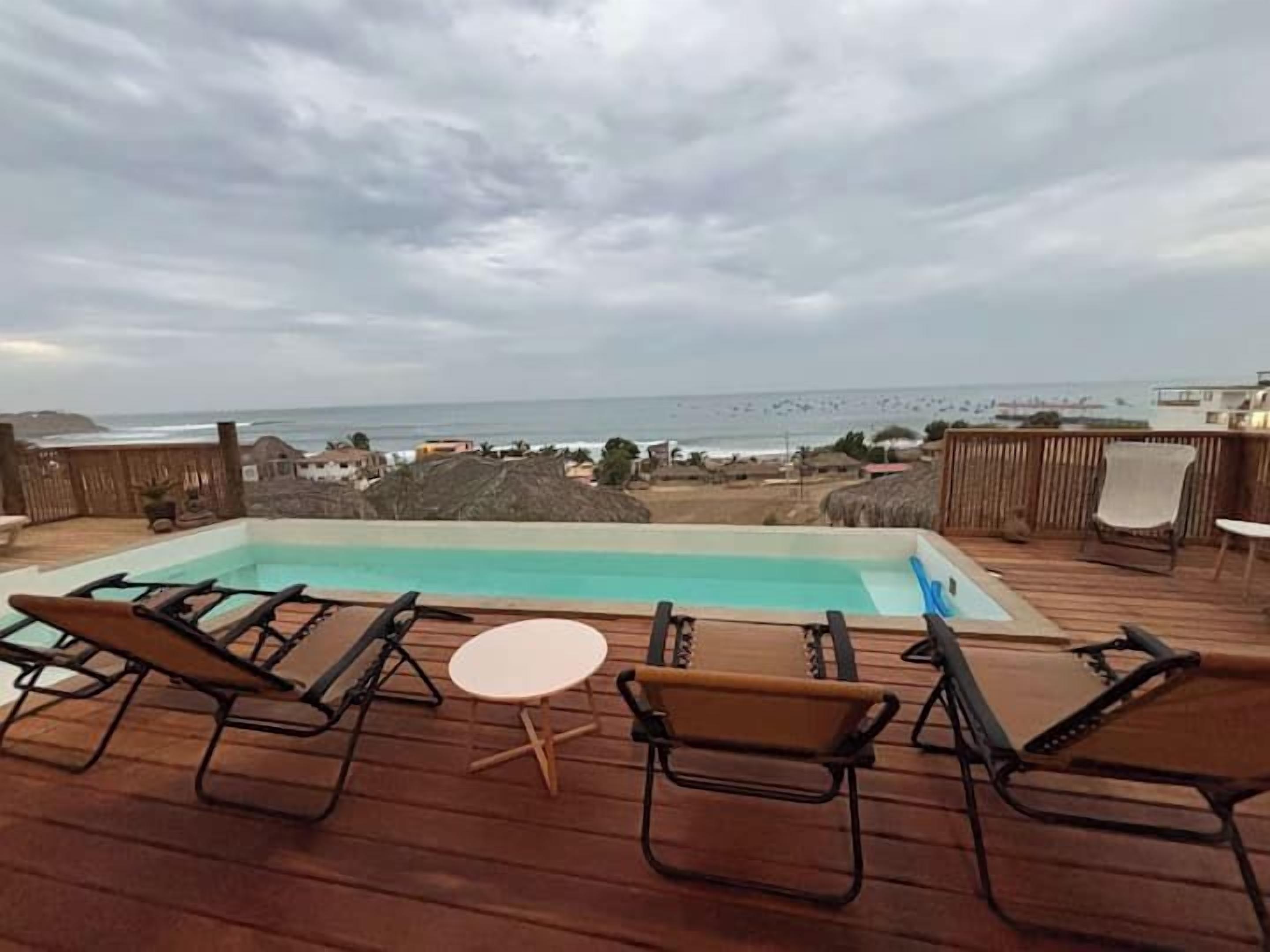 Um deck de madeira com piscina, espreguiçadeiras e uma mesa.