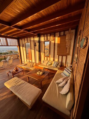 Amplia sala de estar con techo de madera, ventanas grandes y vista al mar.