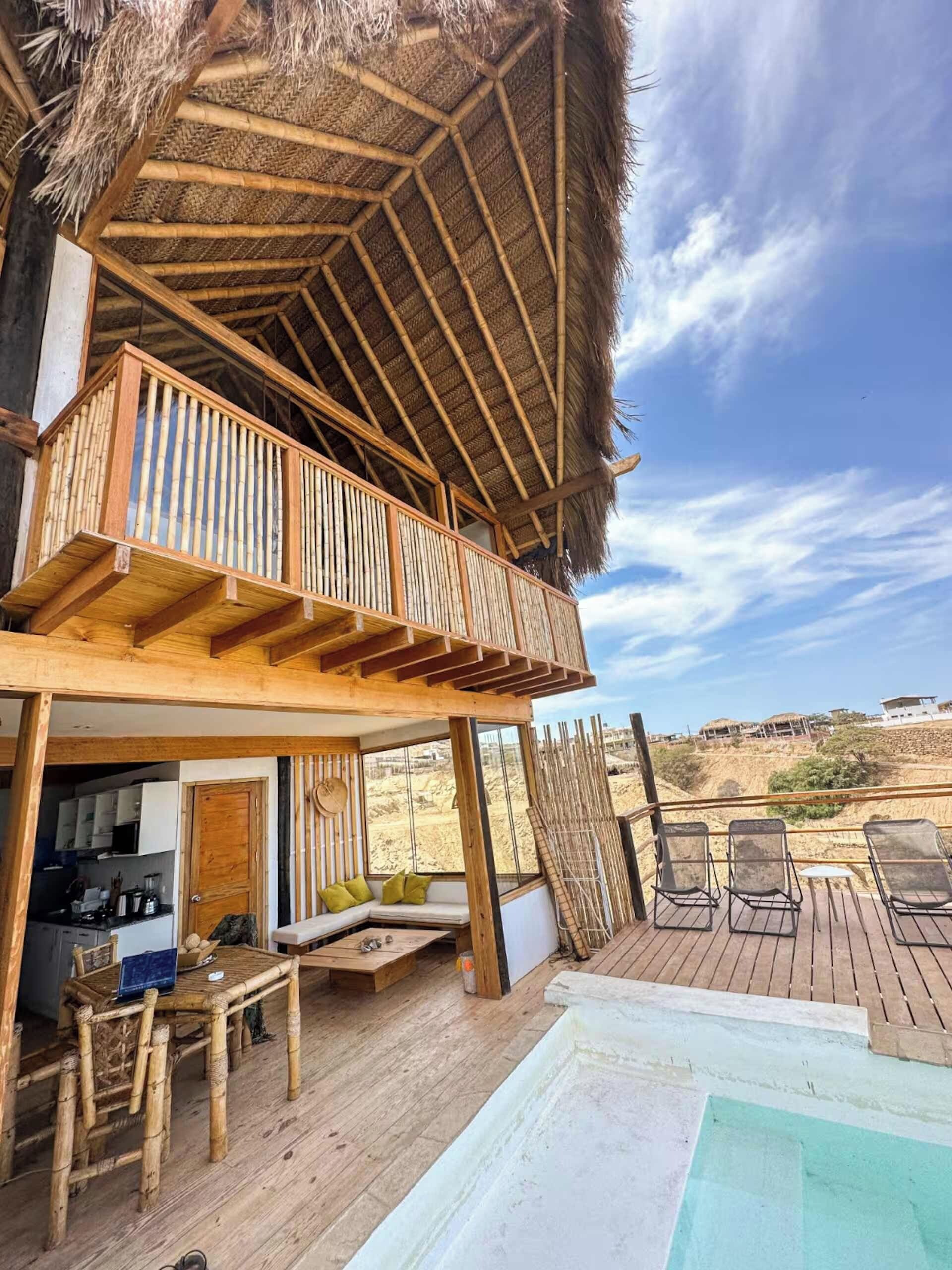 Um deck de madeira com piscina, área de refeições e cozinha.