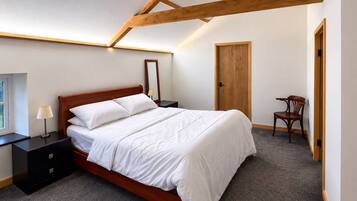 A bedroom with a wooden bed, a nightstand, a chair, and a door.