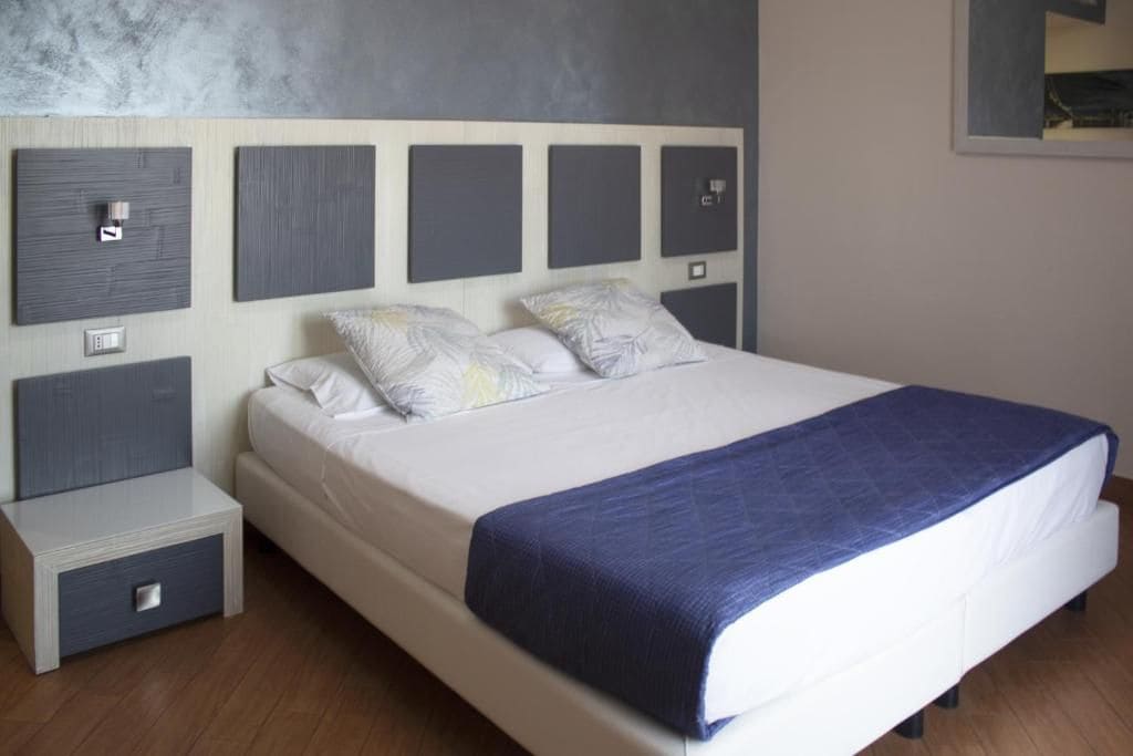 Un dormitorio moderno con una cama grande, una mesita de noche y un cabecero con iluminación integrada.