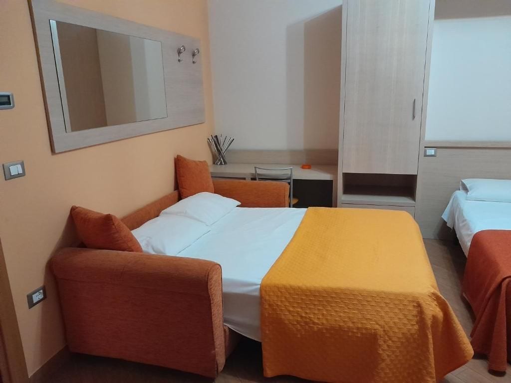 A hotel room with a bed, a desk, and a wardrobe.