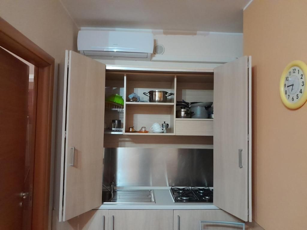 Una cocina compacta con estufa a gas, repisas con utensilios de cocina y un reloj en la pared.