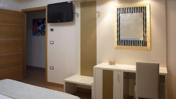 A bedroom with a bed, a desk, a chair, a television, and a mirror.