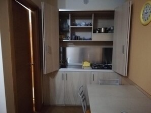 A compact kitchen with a dining table, cabinets, and a stove.