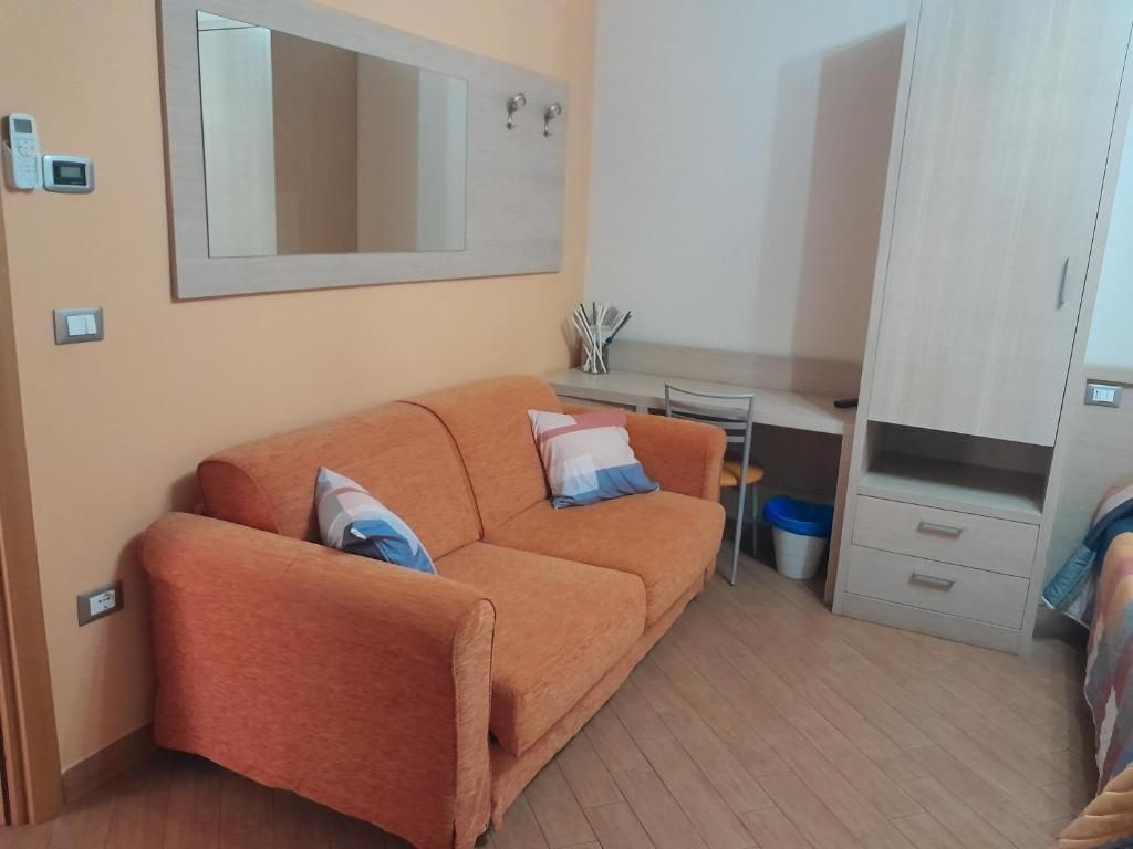 Una habitación funcional con sofá, escritorio y armario.