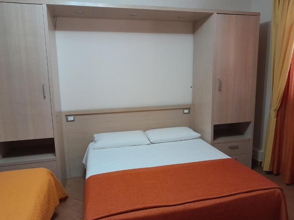 A hotel room with a bed, a wardrobe, and a small table.