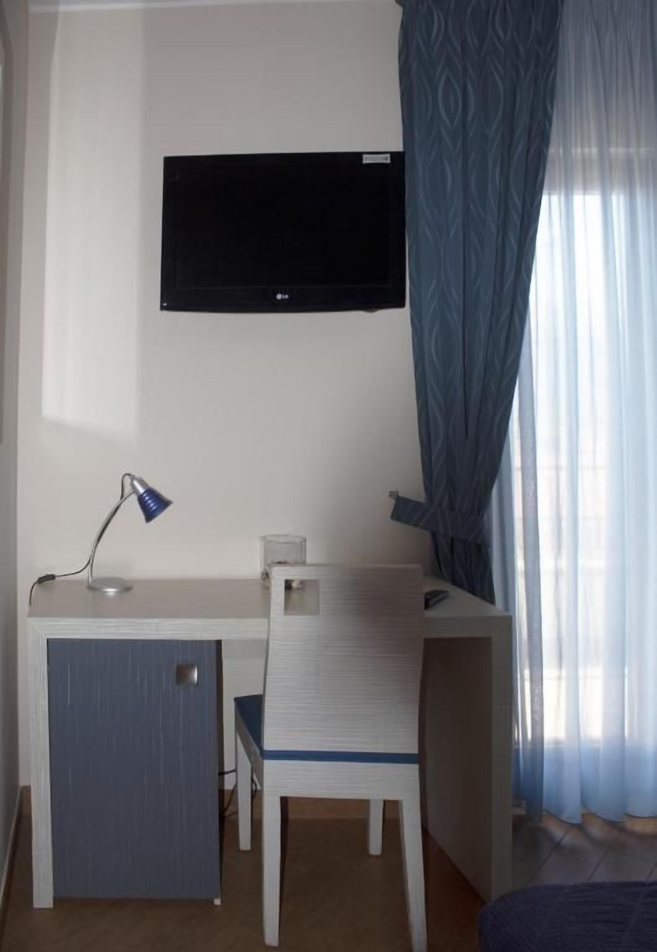 Una camera d'albergo con scrivania, sedia, televisione e un letto.