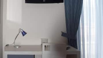 Una camera d'albergo con scrivania, sedia, televisione e un letto.