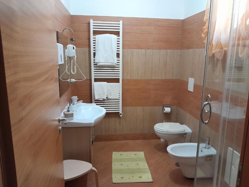 Un baño pequeño con ducha, inodoro, lavabo y barra para toallas.