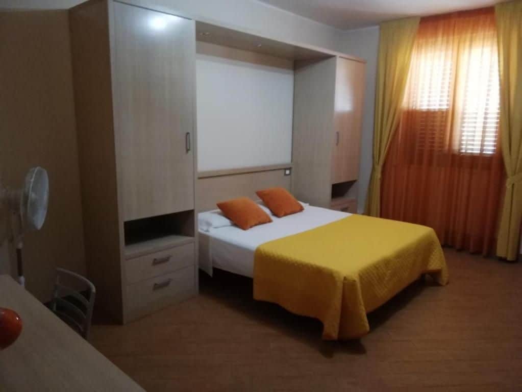 Un dormitorio con cama, armario, escritorio y silla.