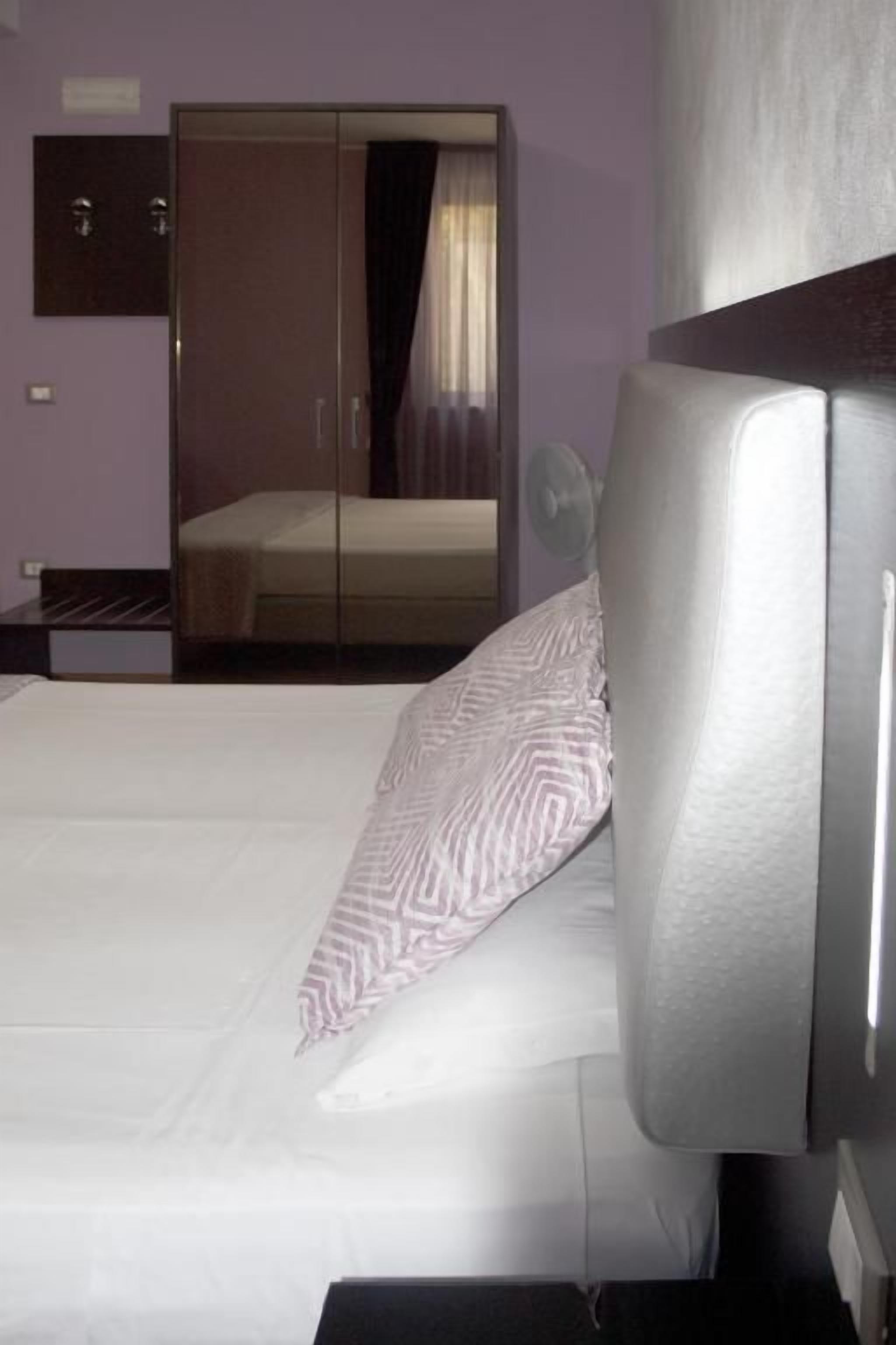 A hotel room with a bed, a wardrobe, and a mirror.