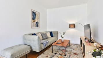 Una sala de estar con sofá, mesa de centro, mueble para televisor e iluminación instalada en la pared.