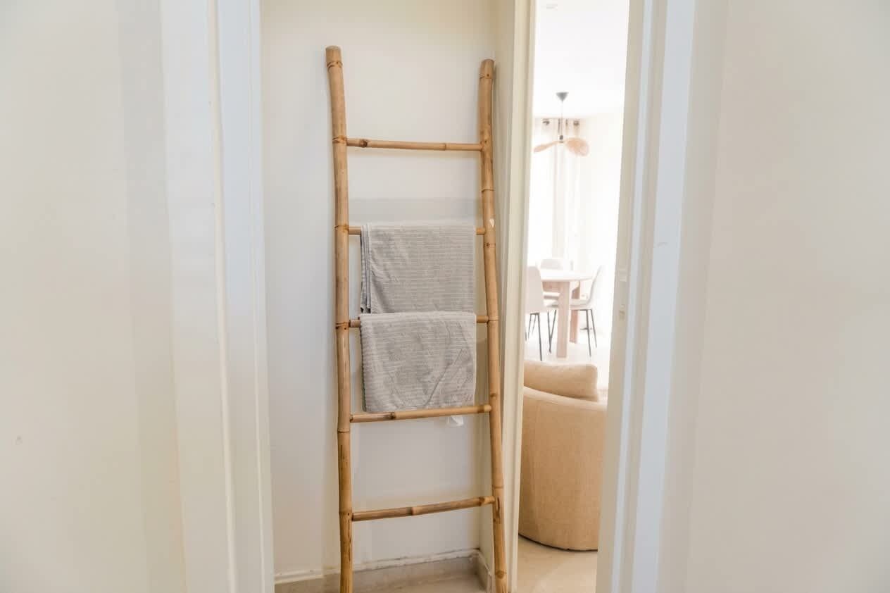 A bamboo ladder leaning against a wall with two towels hanging on it.