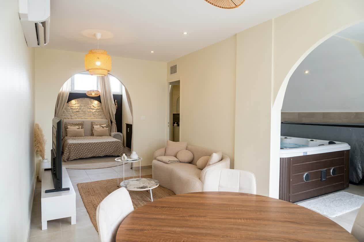 Une chambre à coucher moderne avec un lit, un coin salon doté d’une table et un jacuzzi.