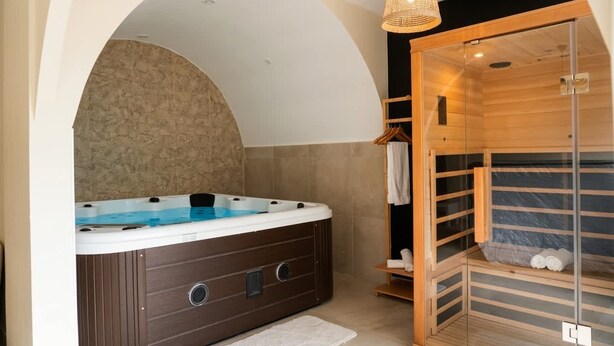 Um espaço de spa com hidromassagem, sauna de madeira e área de chuveiro envidraçada.