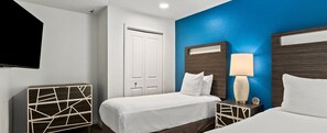A hotel room with a bed, bedside tables, a lamp, and a door. - Wyndham Tropicana 2 bdrm in Las Vegas for F1 weekend w/ outdoor pool and hot tub (Las Vegas)