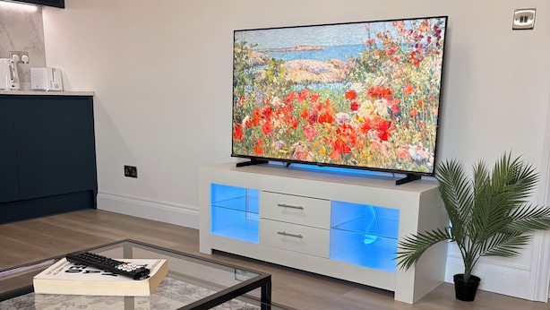 Ein modernes Wohnzimmer mit einem Flachbildfernseher, einem Glastisch und einem Teppich mit Muster.