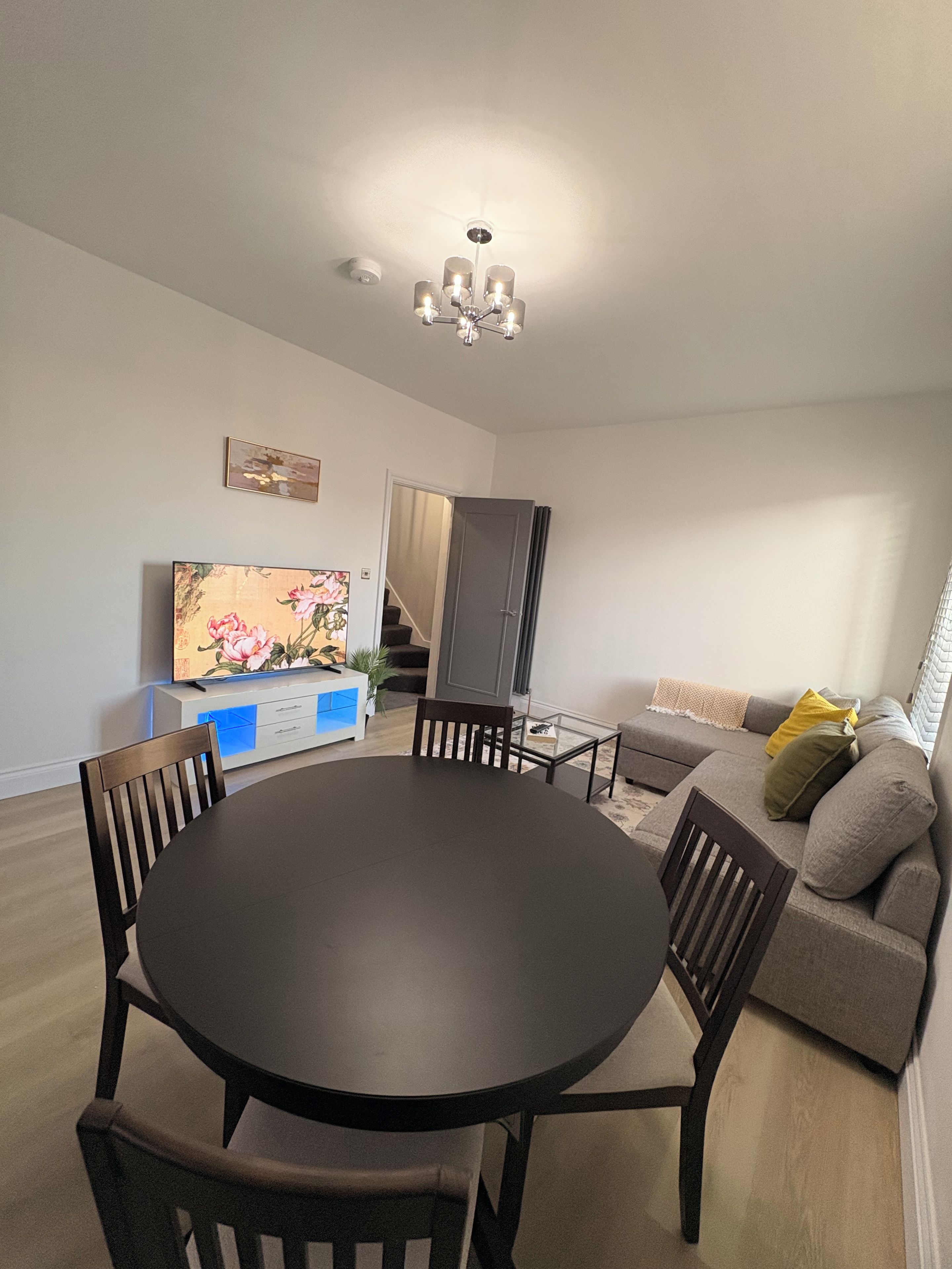 A dining area with a round table and chairs, a sofa, and a television.
