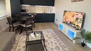 Ein modernes Wohnzimmer mit Essbereich, Küche und Fernseher.