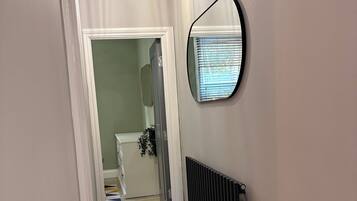 A hallway with a radiator, a mirror, and a patterned rug.