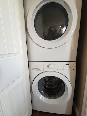A stacked washer and dryer unit with a control panel and a door. - Ocean View Haven, Ocean Views • Stunning Sunsets • Fully Equipped Home •  (Nanaimo)