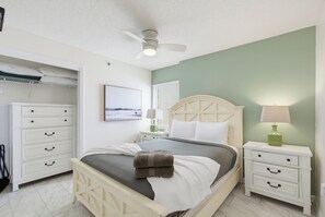 A bedroom with a bed, bedside tables, a wardrobe, a ceiling fan, and a window with blinds. - Four Winds 801 - Beachfront Corner - Pool & Hot Tub (Orange Beach)