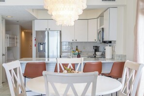 A modern kitchen with white cabinets, stainless steel appliances, and a central island with seating. - Four Winds 801 - Beachfront Corner - Pool & Hot Tub (Orange Beach)