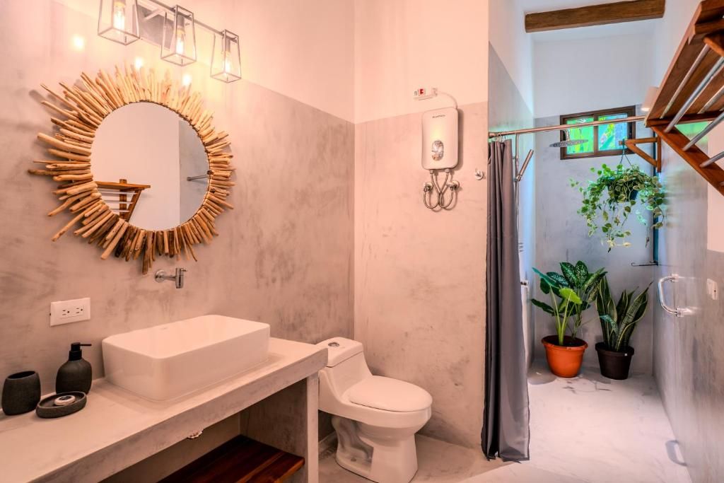 A modern bathroom with a round mirror, white sink, and toilet.
