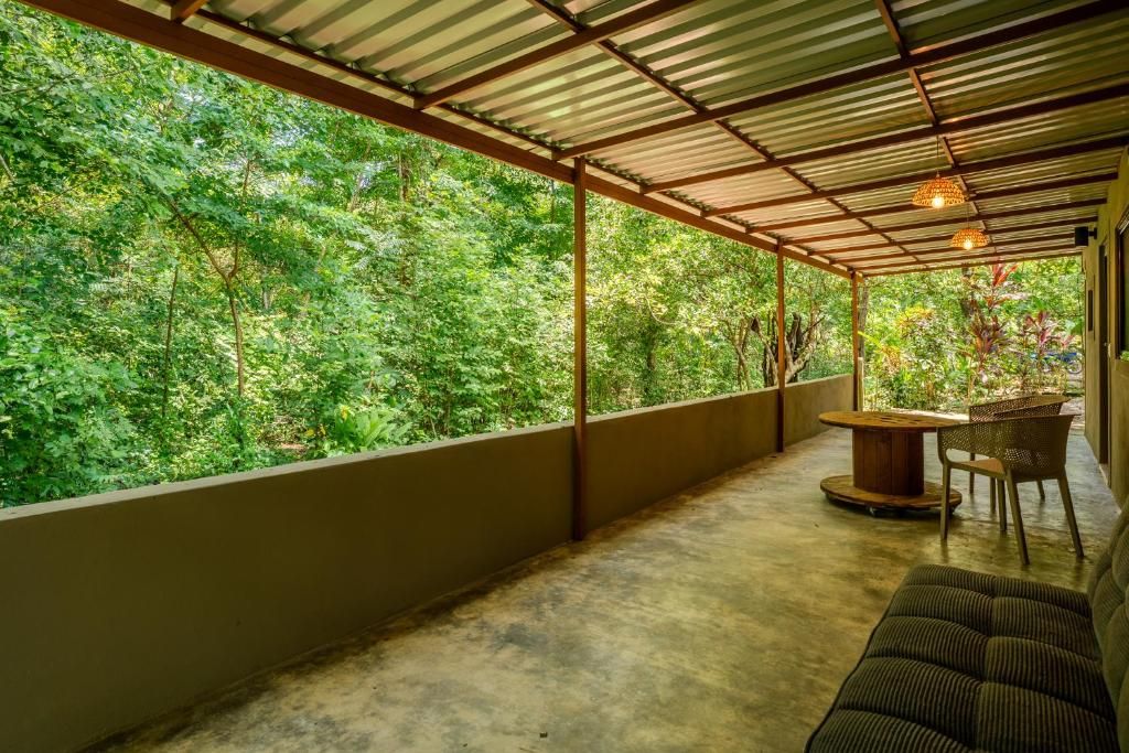 Un espacio al aire libre techado con piso de concreto, una mesa con sillas y un sofá.