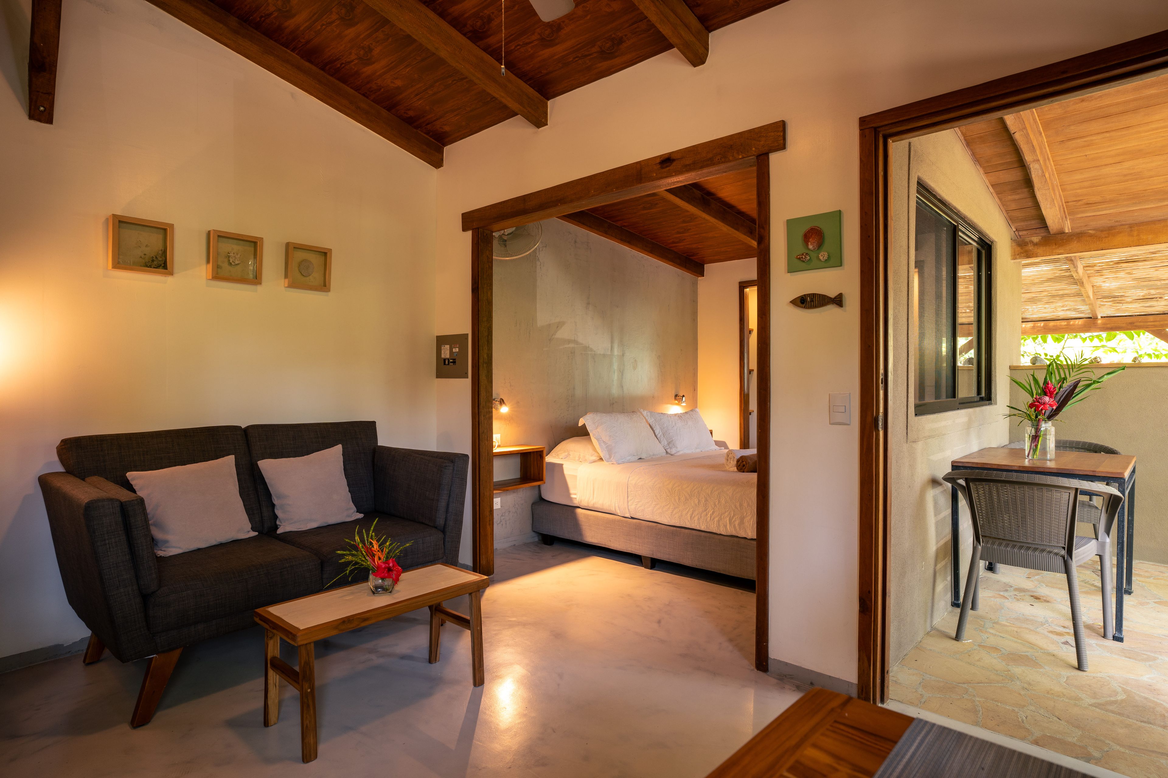 Una habitación acogedora con sofá, una mesita y una cama. Tiene techo de madera y ventana con vistas.