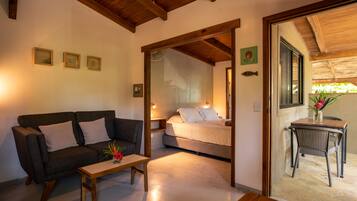 Una habitación acogedora con sofá, una mesita y una cama. Tiene techo de madera y ventana con vistas.