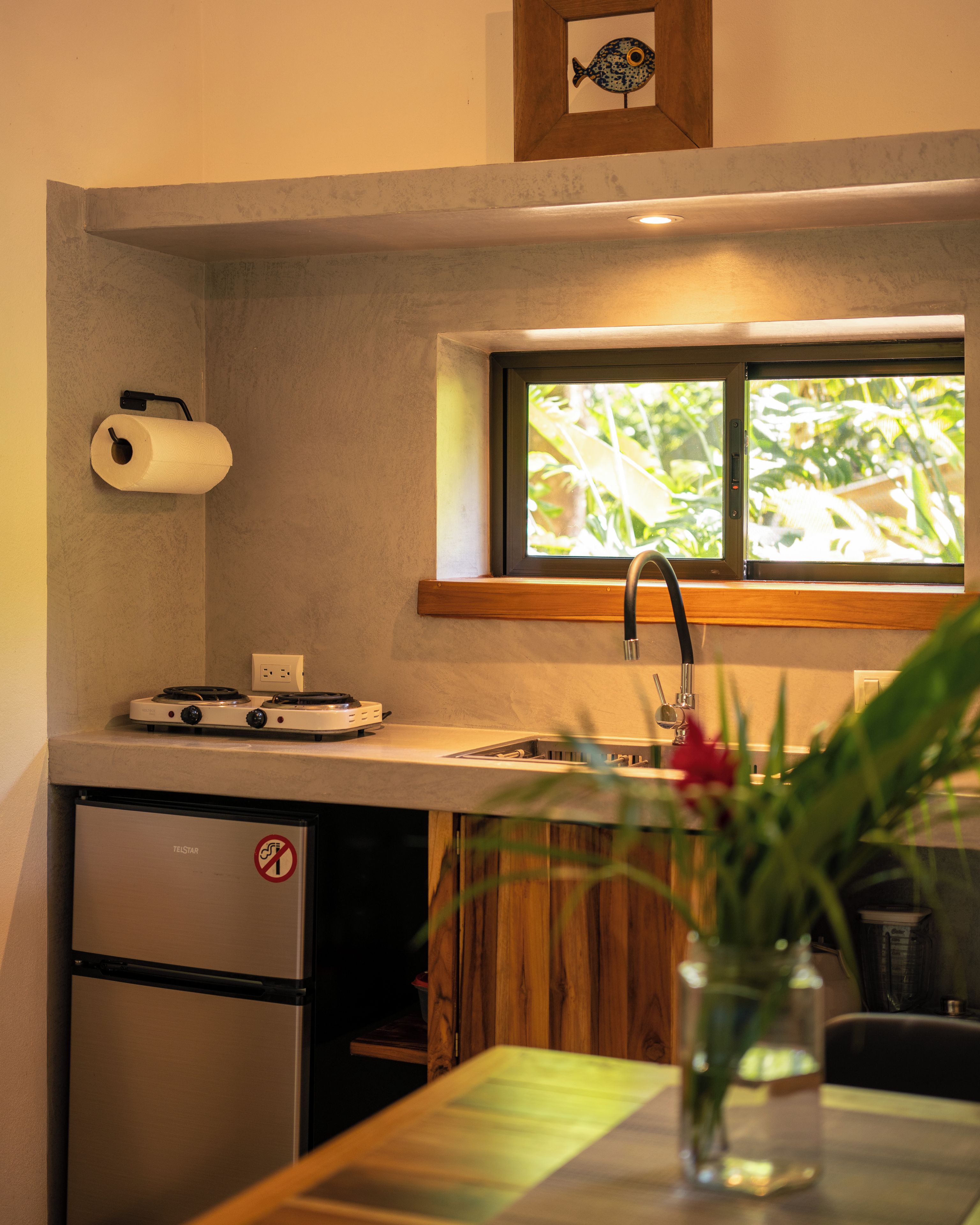 A compact kitchen with a built-in stove, a small refrigerator, and a window above the sink.