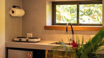 A compact kitchen with a built-in stove, a small refrigerator, and a window above the sink.