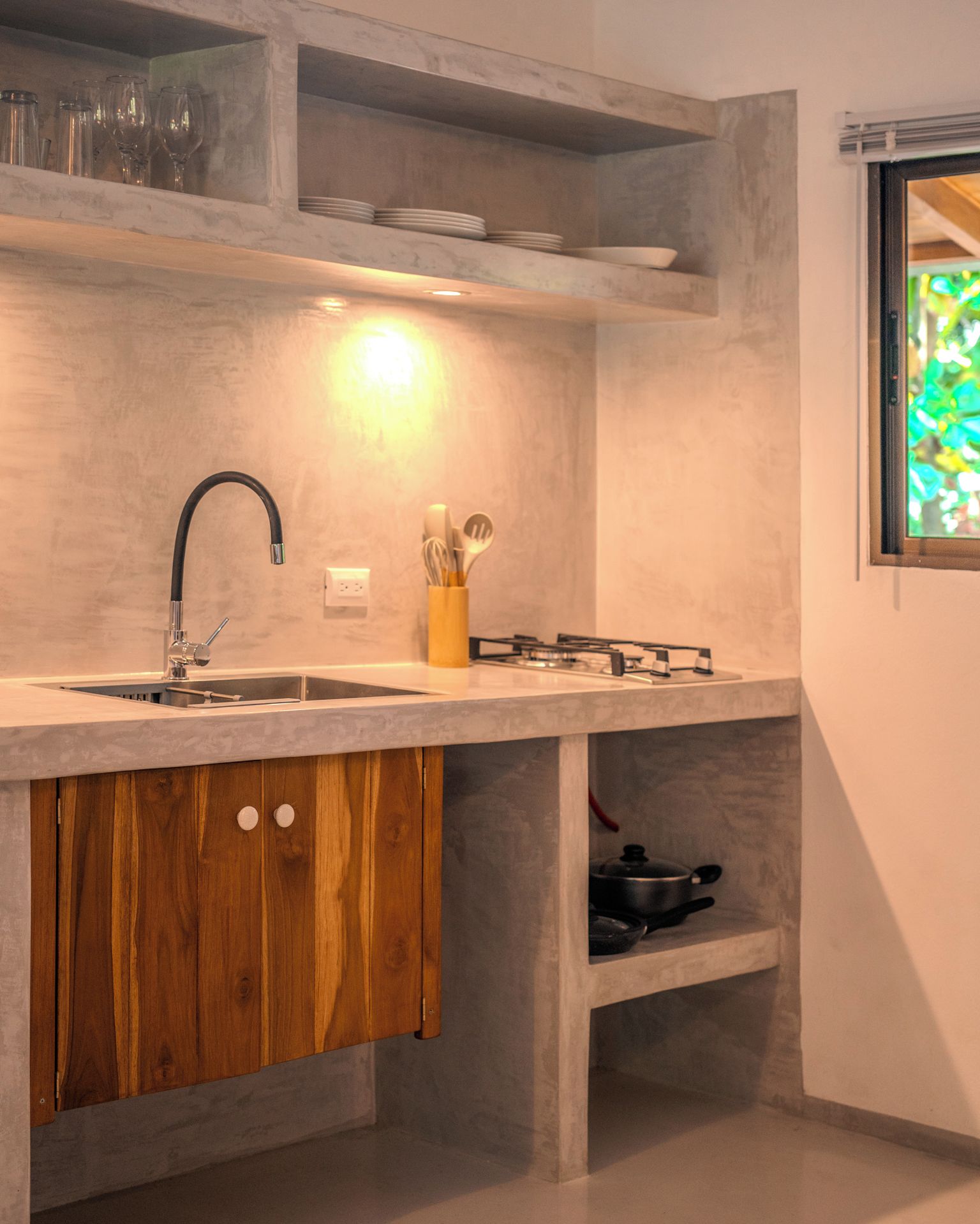 A kitchen with a built-in sink, a gas stove, wooden cabinets, and a window with a view.